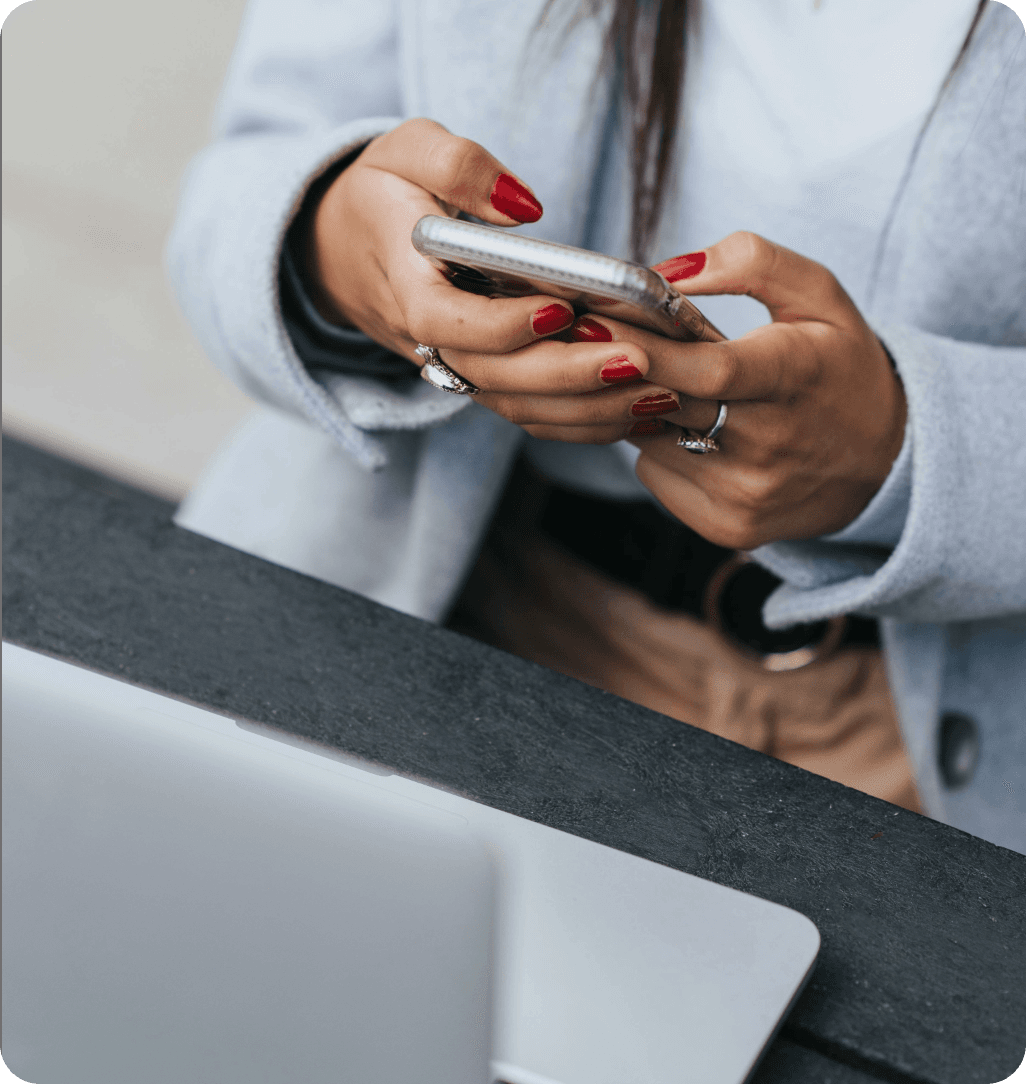 Une personne tient un smartphone devant son ordinateur portable.